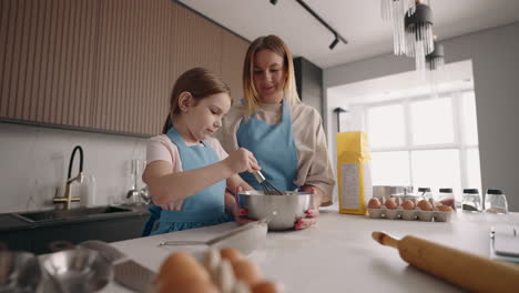 woman and her little helper are cooking together in home little daughter and mother are making cake