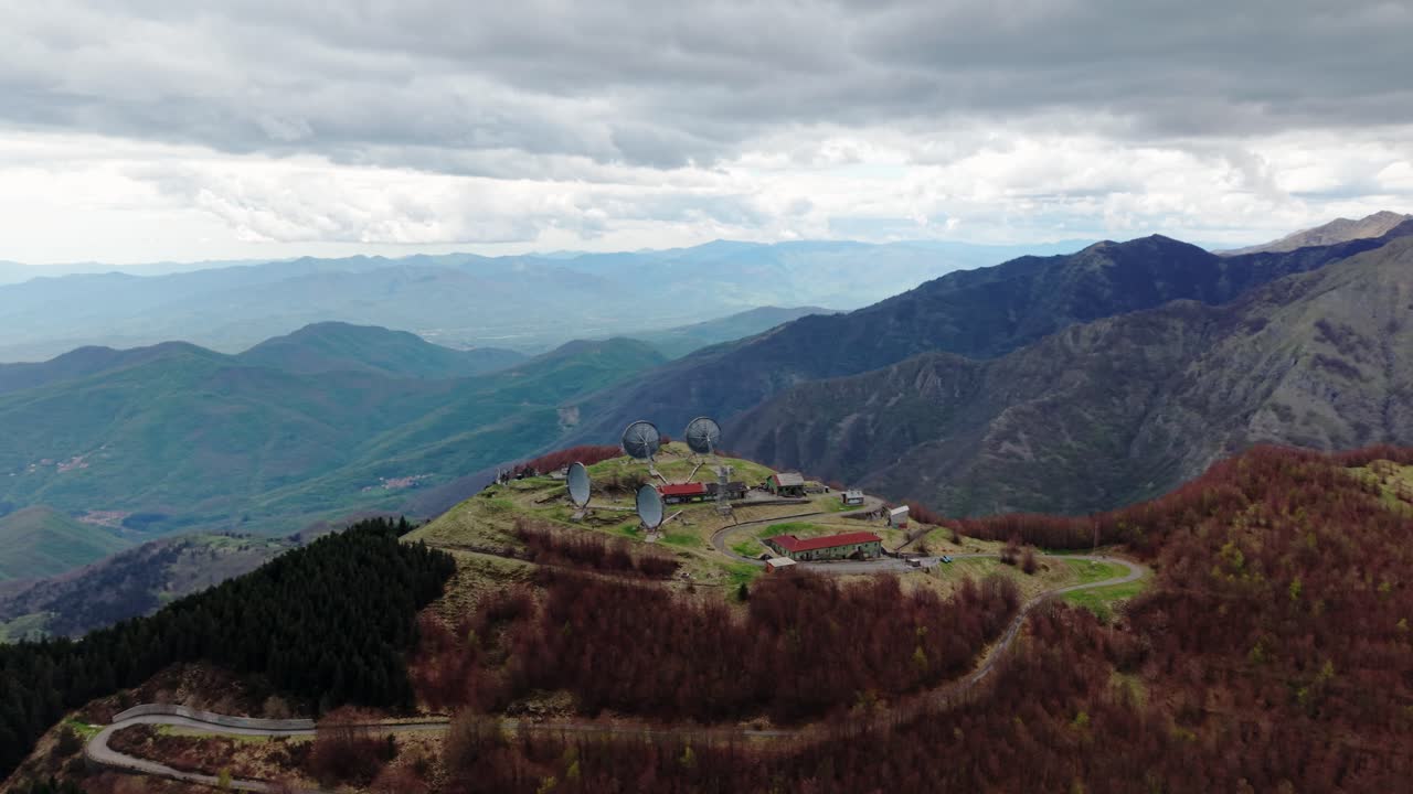 Old radar station on a remote mountaintop under cloudy skies, aerial view