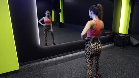 chica atractiva posando frente a un espejo en el gimnasio