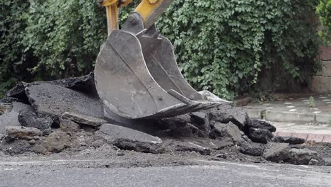 excavator digging up asphalt on a road