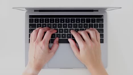 manos ocupadas escribiendo en el teclado del portátil