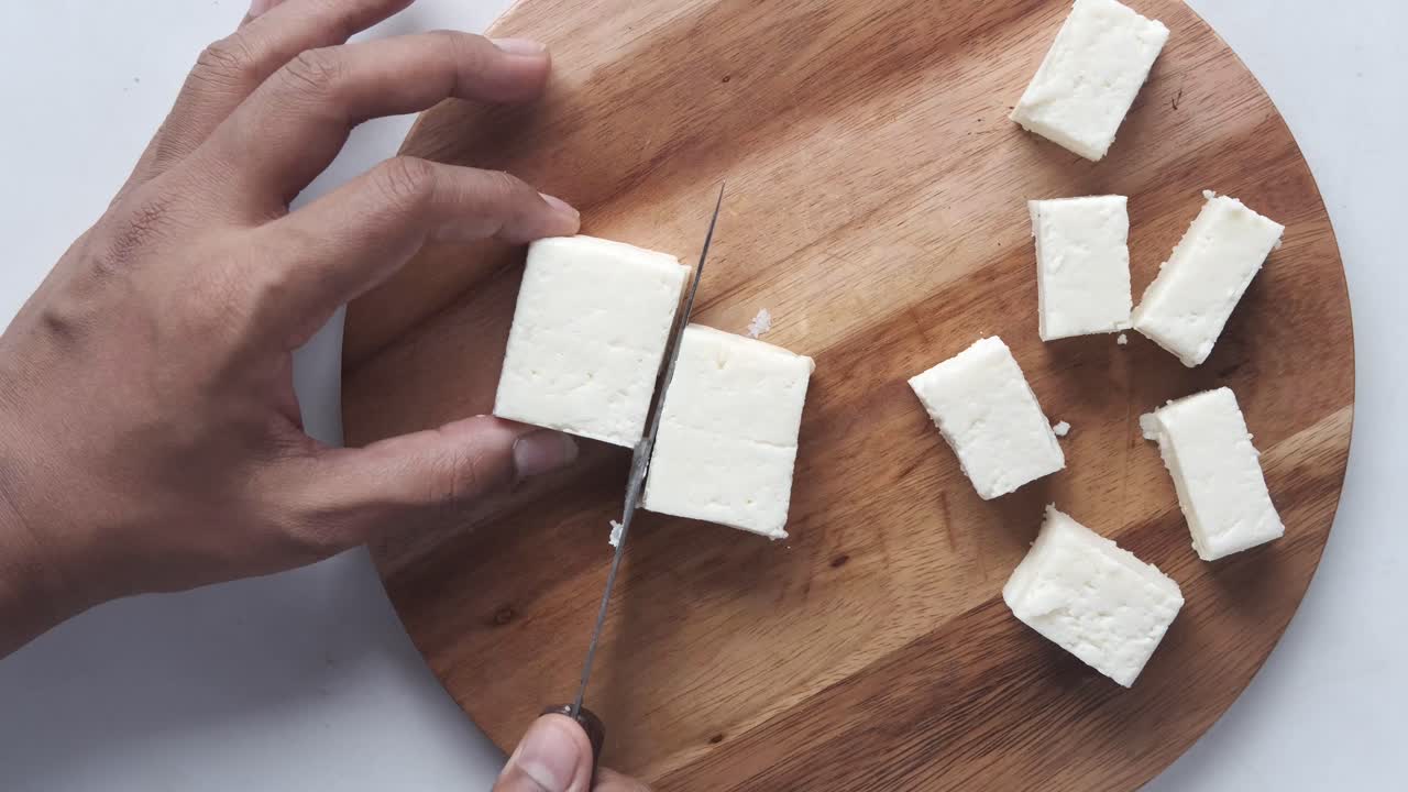 cortar el queso paneer en una tabla de madera
