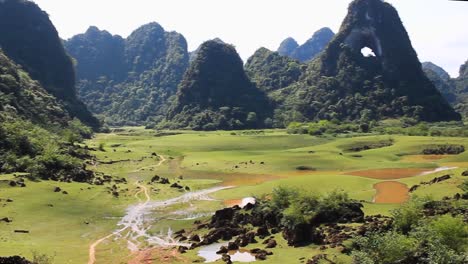 breathtaking-view-of-the-mountains-in-Cao-Bang-North-Vietnam-with-horses-in-a-field-and-an-eye-in-the-mountains,-pan-right