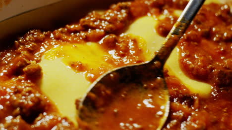 detail close up of spoon spreading meat tomato sauce, cooking lasagne process