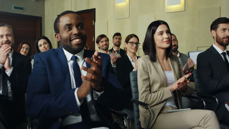 close-up view of multiethnic business people sitting on chairs and clapping in a conference room