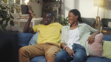 happy african american couple laughing while watching tv at home