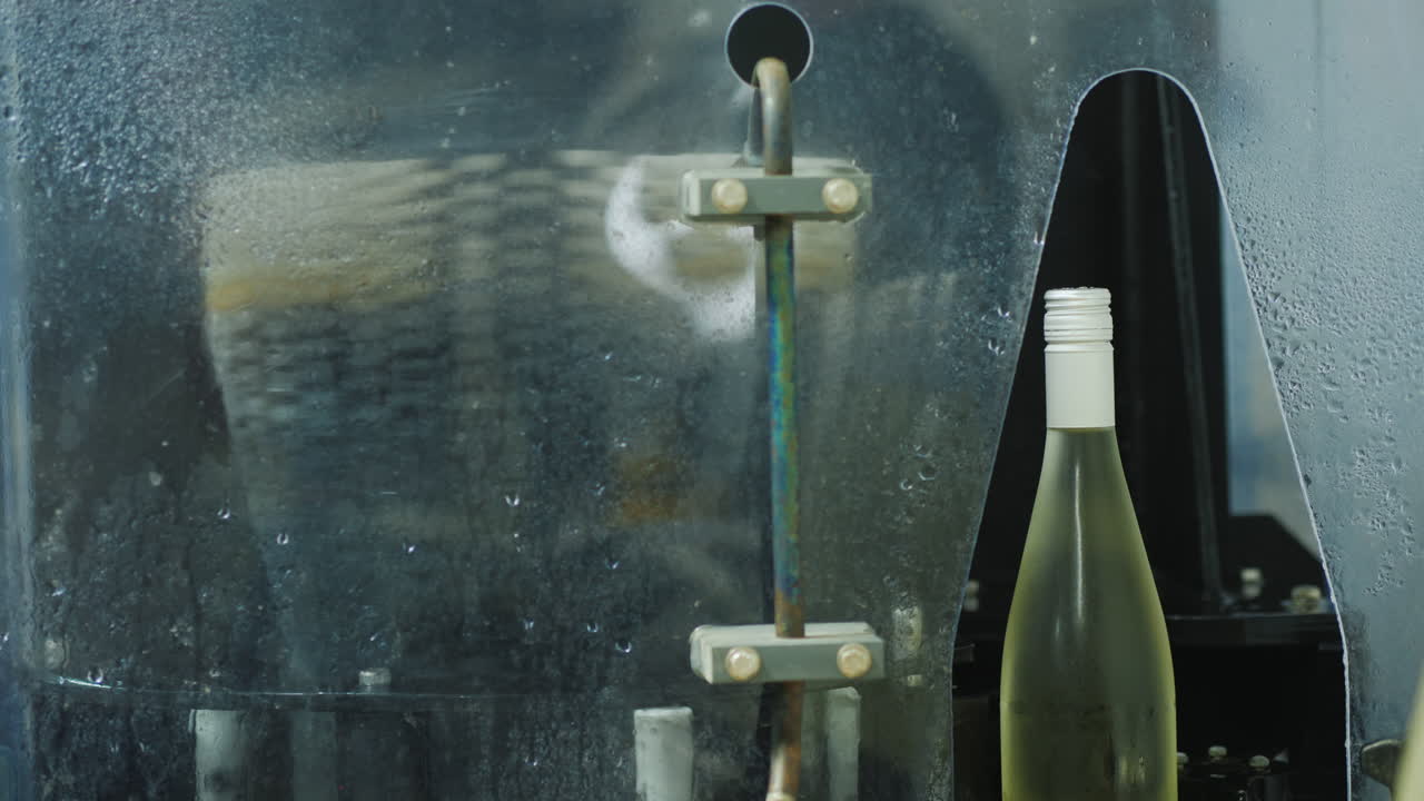 컨베이어를 따라 물로 세척되는 차로 이동하는 와인 병
