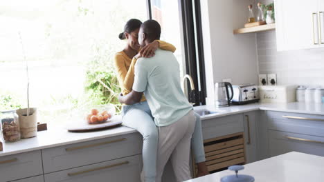 una pareja diversa comparte un momento afectuoso en una cocina moderna, abrazándose