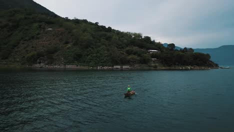 과테말라 아티틀란 호수에서 보트를 타고 노를 젓는 남자의 시네마틱 드론 공중 샷
