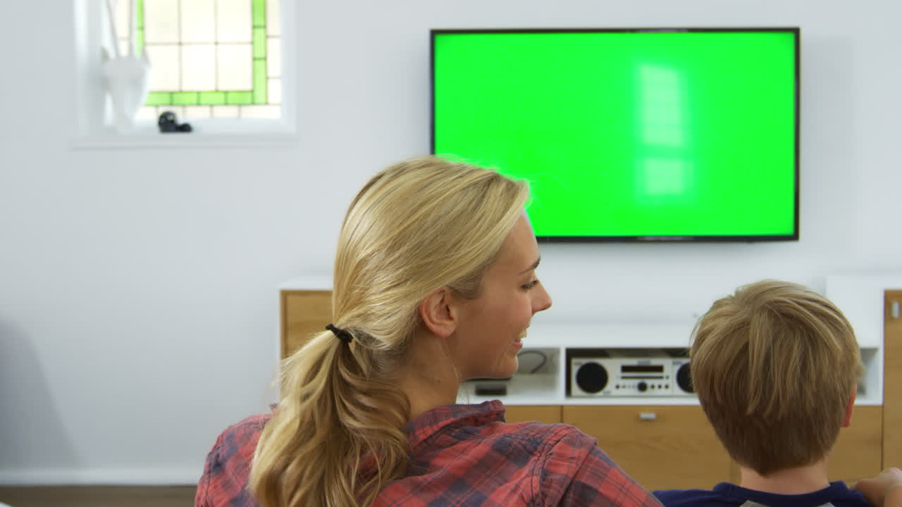 라운지 에서 텔레비전 을 보고 소파 에 앉아 있는 가족 의 뒷면