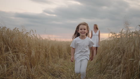 En-Cámara-Lenta,-Una-Niña-De-4-5-Años-Corre-En-Un-Campo-Al-Atardecer-Mirando-La-Cámara-Feliz-Y-Libre.-Infancia-Feliz.-Niña-Corriendo-En-El-Campo-Al-Atardecer