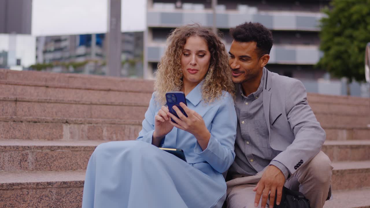 Couple sitting on stairs looking at phone