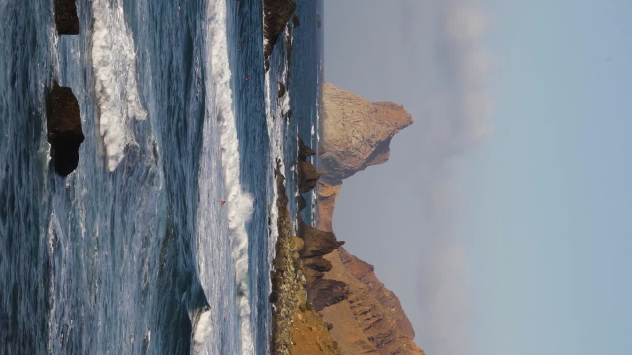surfistas en el océano tratando de atrapar la ola para surfear en la playa de benijo, tenerife, de mano