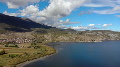 village on shore of prespa lake, water reflection mountain and clouds on relaxing scenery