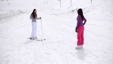 young woman learning to ski from a friend
