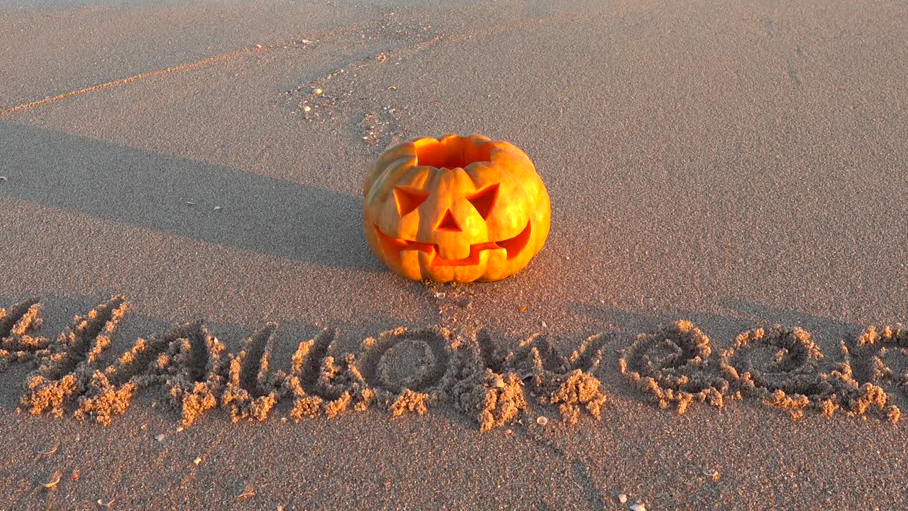 Calabaza de Halloween espeluznante. Inscripción Halloween en la arena de la playa