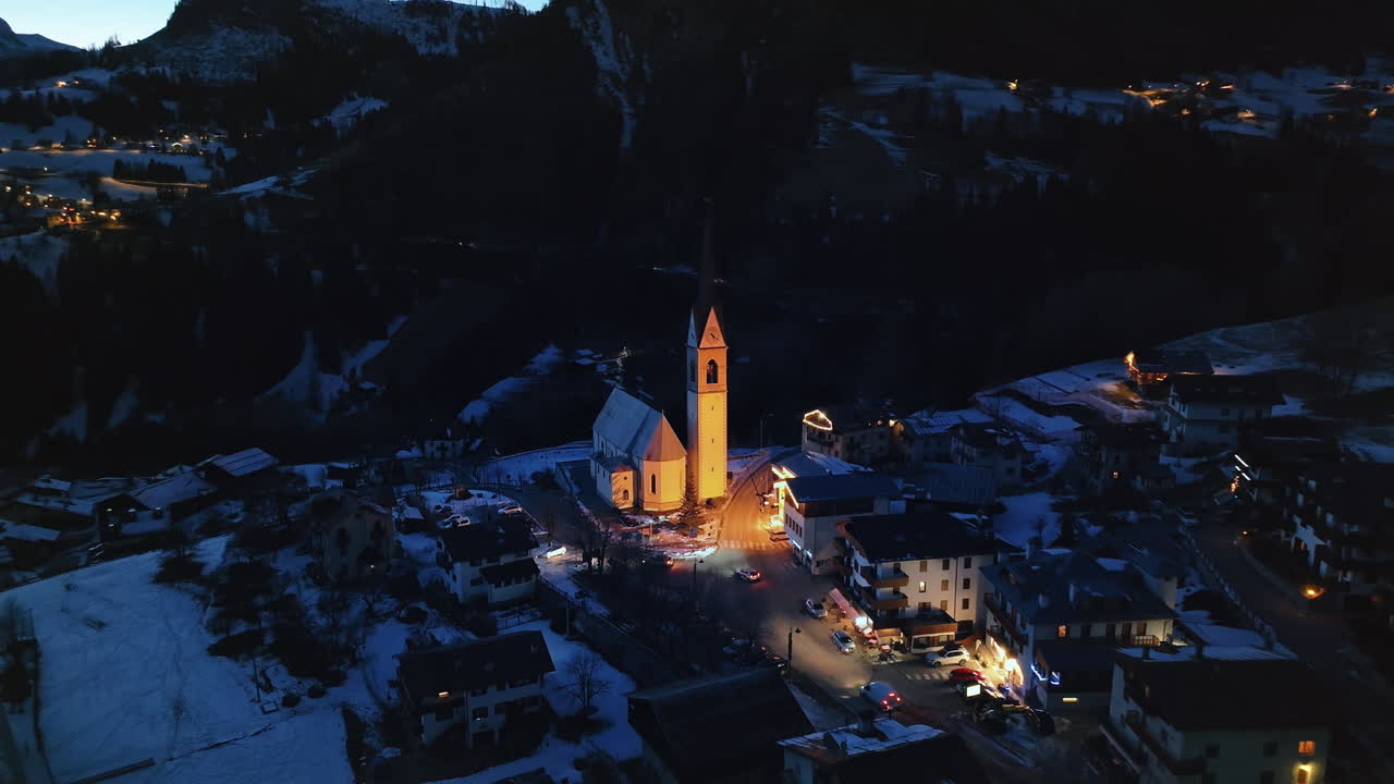 Aerial drone view of the San Lorenzo Church illuminated at night in the Selva di Cadore comune in Dolomites, Italy