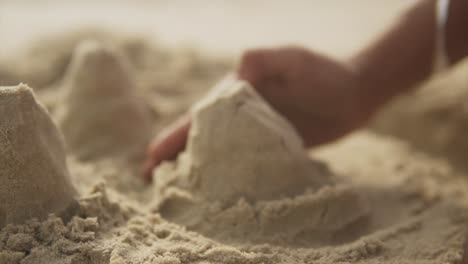 Blurred-image-of-forming-a-sand-castle-on-the-beach-with-his-hand---close-up,-slow-motion