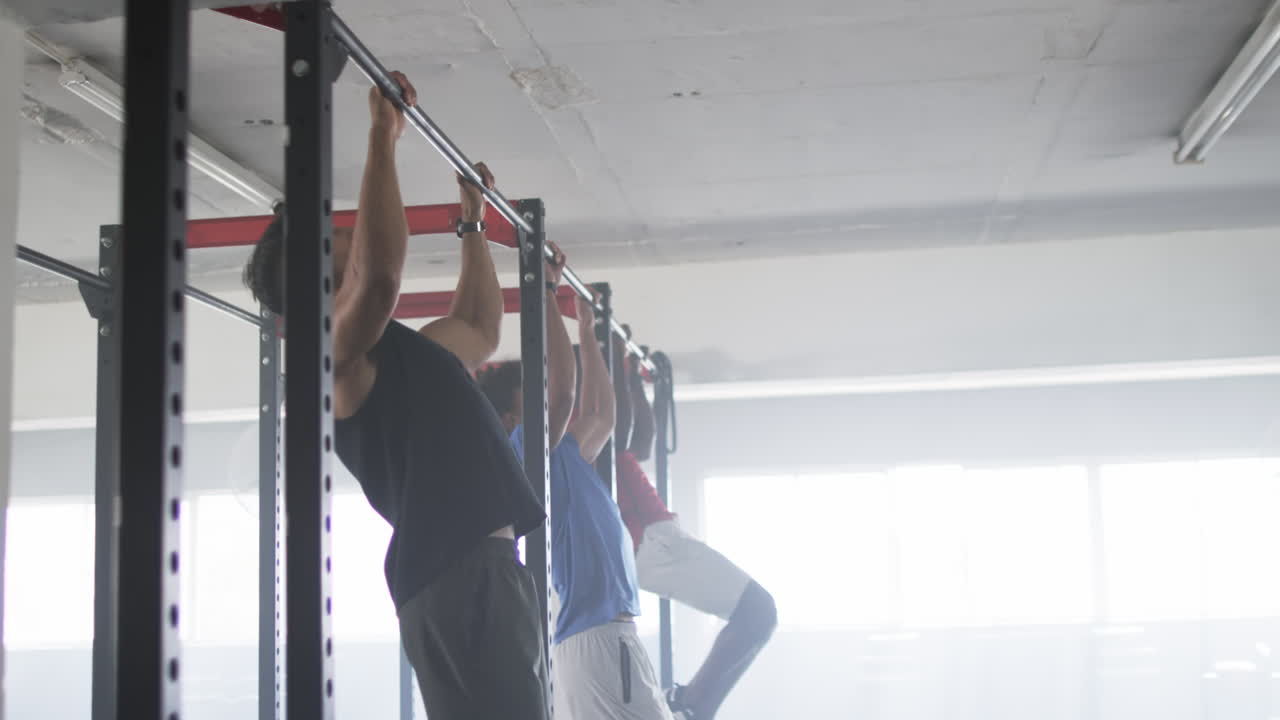Doing pull-ups, men exercising on pull-up bars in gym, building strength, copy space