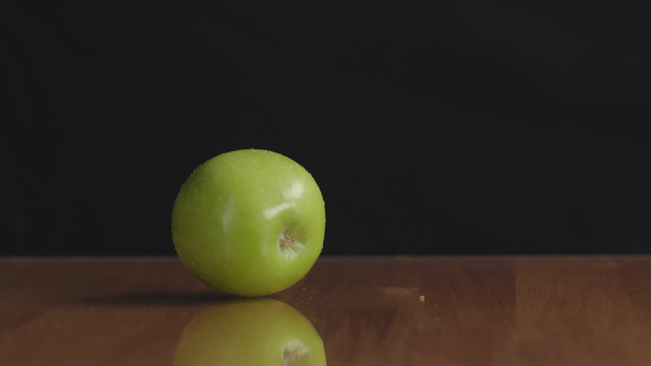 Drejer et grønt æble på bordet