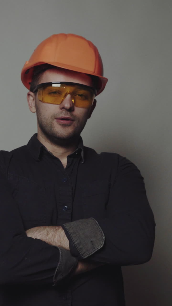 Portrait of young engineer with helmet. Young construction worker in hard hat on gray background