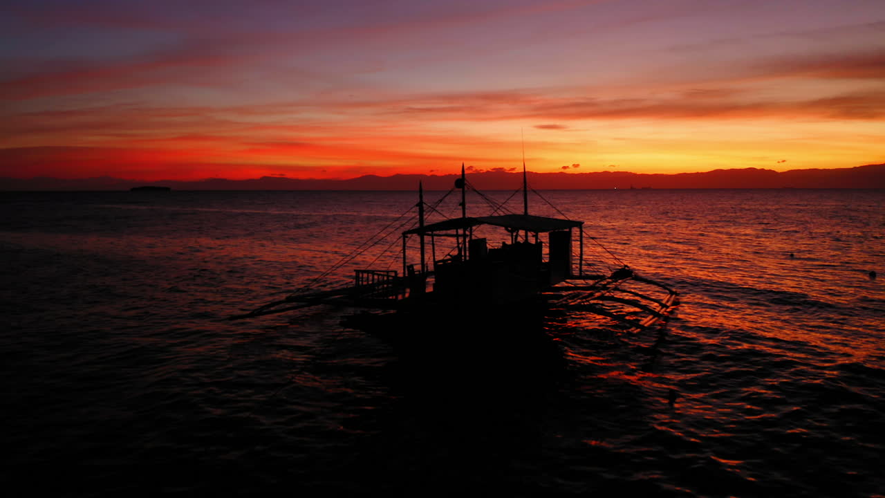 clásico barco araña filipino en el mar durante una puesta de sol naranja en moalboal, cebu, filipinas