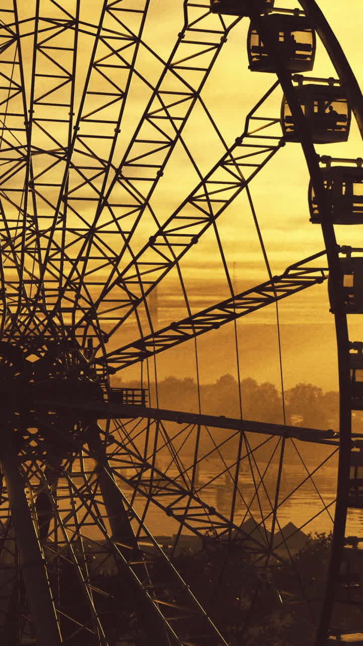 Ferris wheel silhouetted against a stunning sunset over a lake