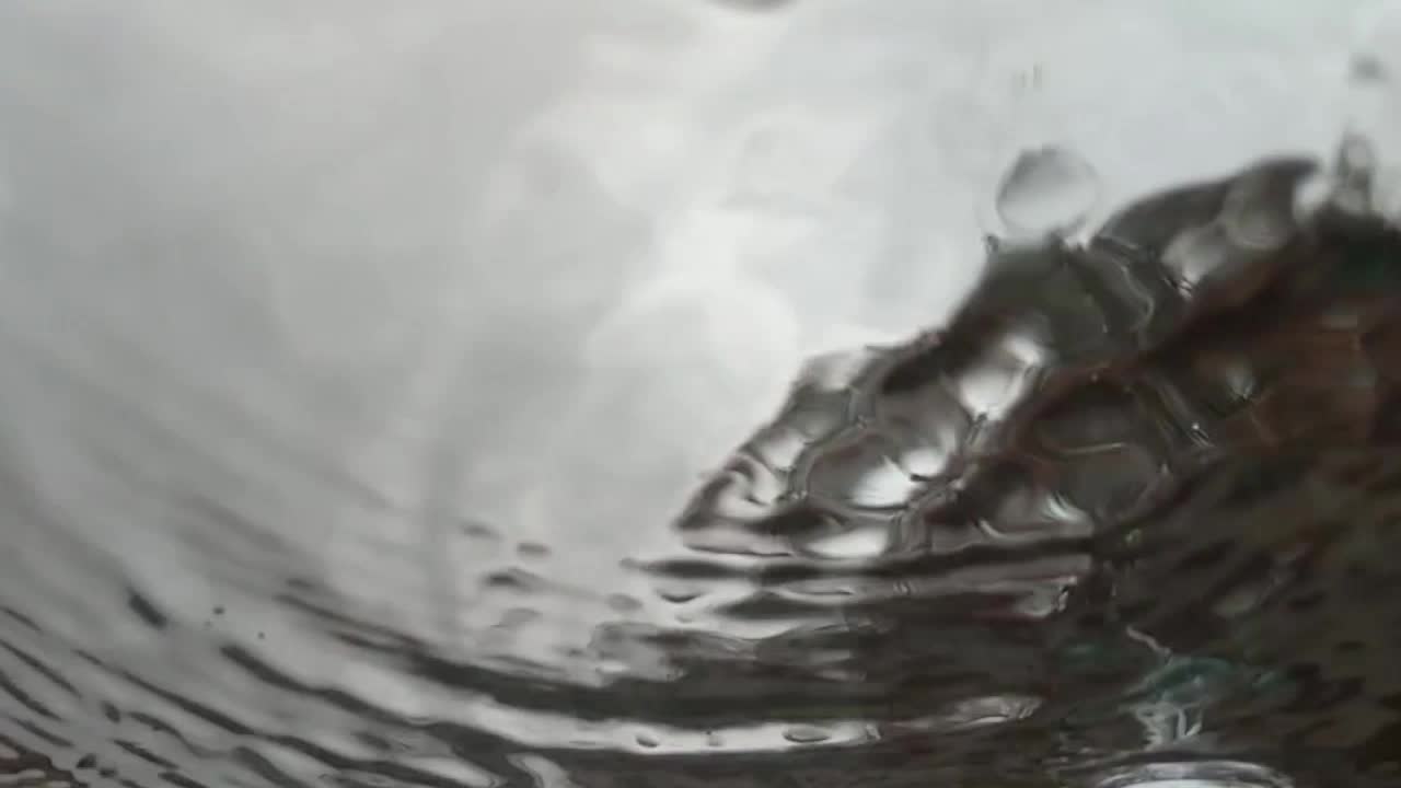 vista abstracta en cámara lenta de las gotas de lluvia aterrizando en el vidrio como se ve desde abajo, debajo, cielo gris