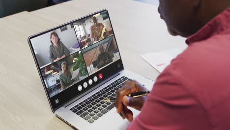 African-american-man-using-laptop-for-video-call,-with-diverse-business-colleagues-on-screen