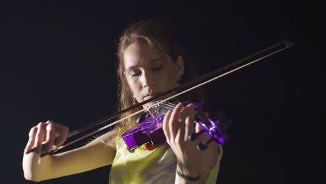 una violinista que toca el violín en la ópera o en el salón de música oscura.