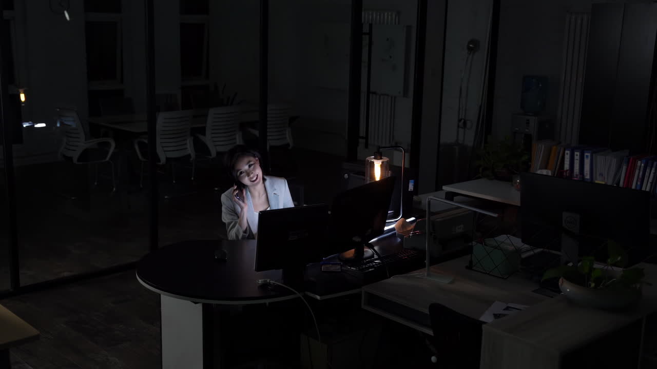 Confident businesswoman company manager is talking on mobile phone, using laptop sitting desk working overtime late night. business negotiations, consultation and effective work in modern environment