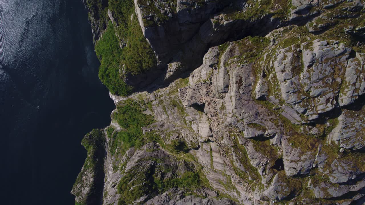 Aerial top down perspective of Preikestolen in Norway with tourists and dramatic fjord landscape.