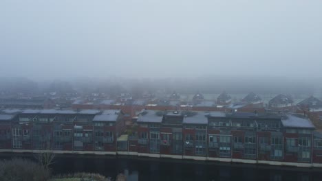 Beautiful-jib-up-of-row-of-houses-near-a-canal-in-thick-mist