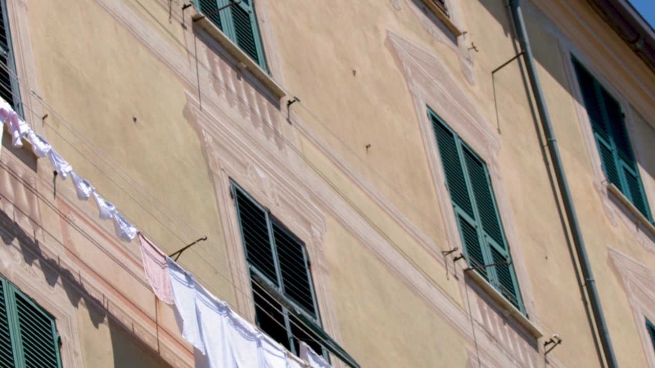 Vista dal basso di bucato bianco che asciuga su uno stendibiancheria fuori da un condominio mediterraneo
