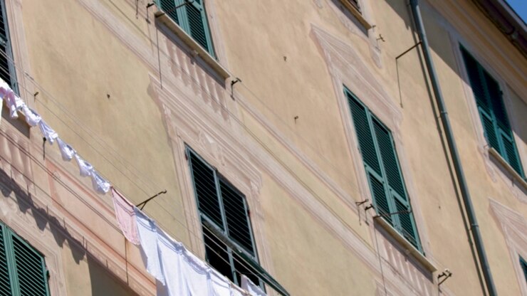 Vista dal basso di bucato bianco che asciuga su uno stendibiancheria fuori da un condominio mediterraneo