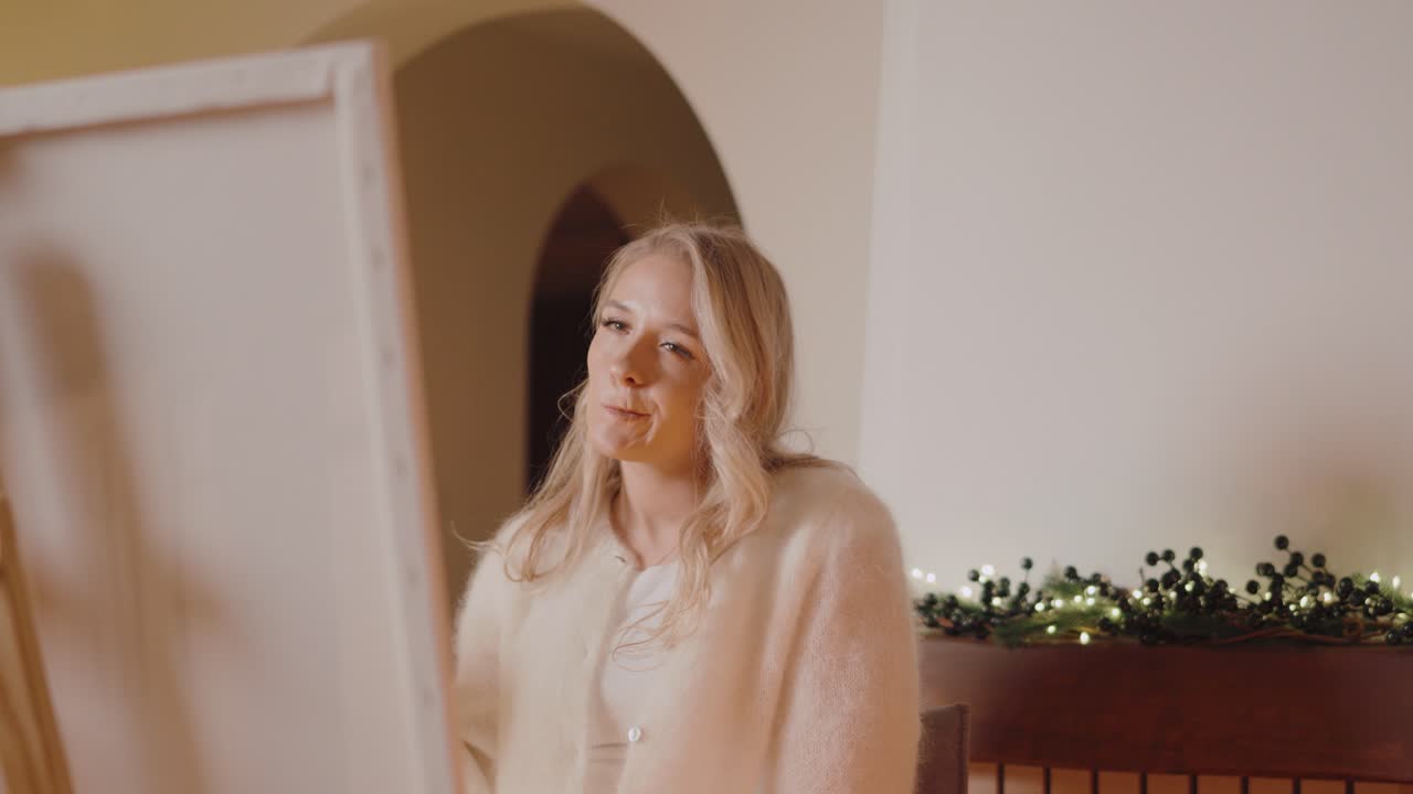 금발의 여성 화가가 차를 마시며 그림을 그리고 있다