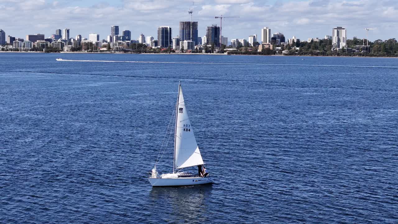 yate de vela con el horizonte de la ciudad de perth en el fondo a lo largo de las aguas del río swan