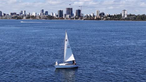 Yate-De-Vela-Con-El-Horizonte-De-La-Ciudad-De-Perth-Al-Fondo-A-Lo-Largo-De-Las-Aguas-Del-Río-Swan