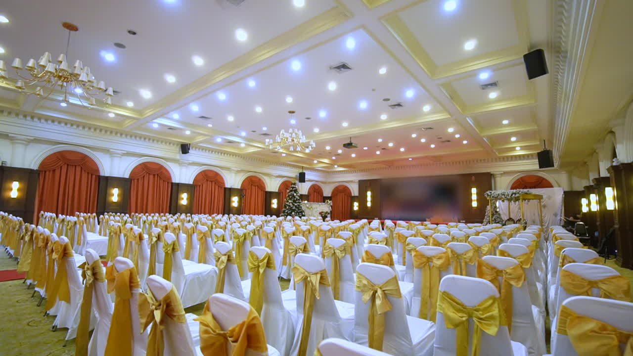 Many white chairs are in the large hall.Tilt shot