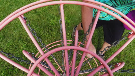 a vibrant pink disc lands in the chains of a disc golf basket, capturing the dynamic moment of a successful throw in a grassy park