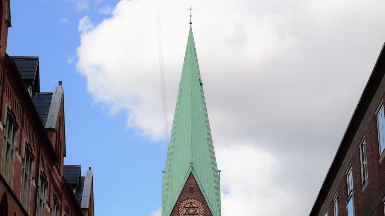 Torre di una chiesa in mattoni e orologio tra edifici residenziali in una città. Copenhagen, Danimarca