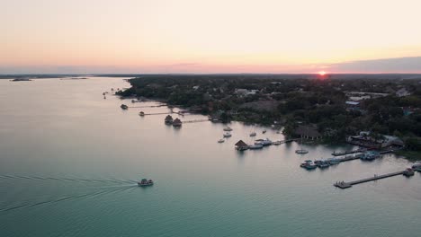 Weitwinkelaufnahme-Einer-Drohnenaufnahme-Einer-Wunderschönen-Szene-Der-Lagune-In-Sieben-Farben-Während-Des-Sonnenuntergangs-Mit-Yachten-Und-Segelbooten,-Die-Zum-Pier-In-Bacalar,-Mexiko,-In-4k-Zurückkehren