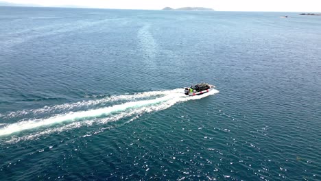 drone footage of fishing boat sailing in dark ocean towards marina