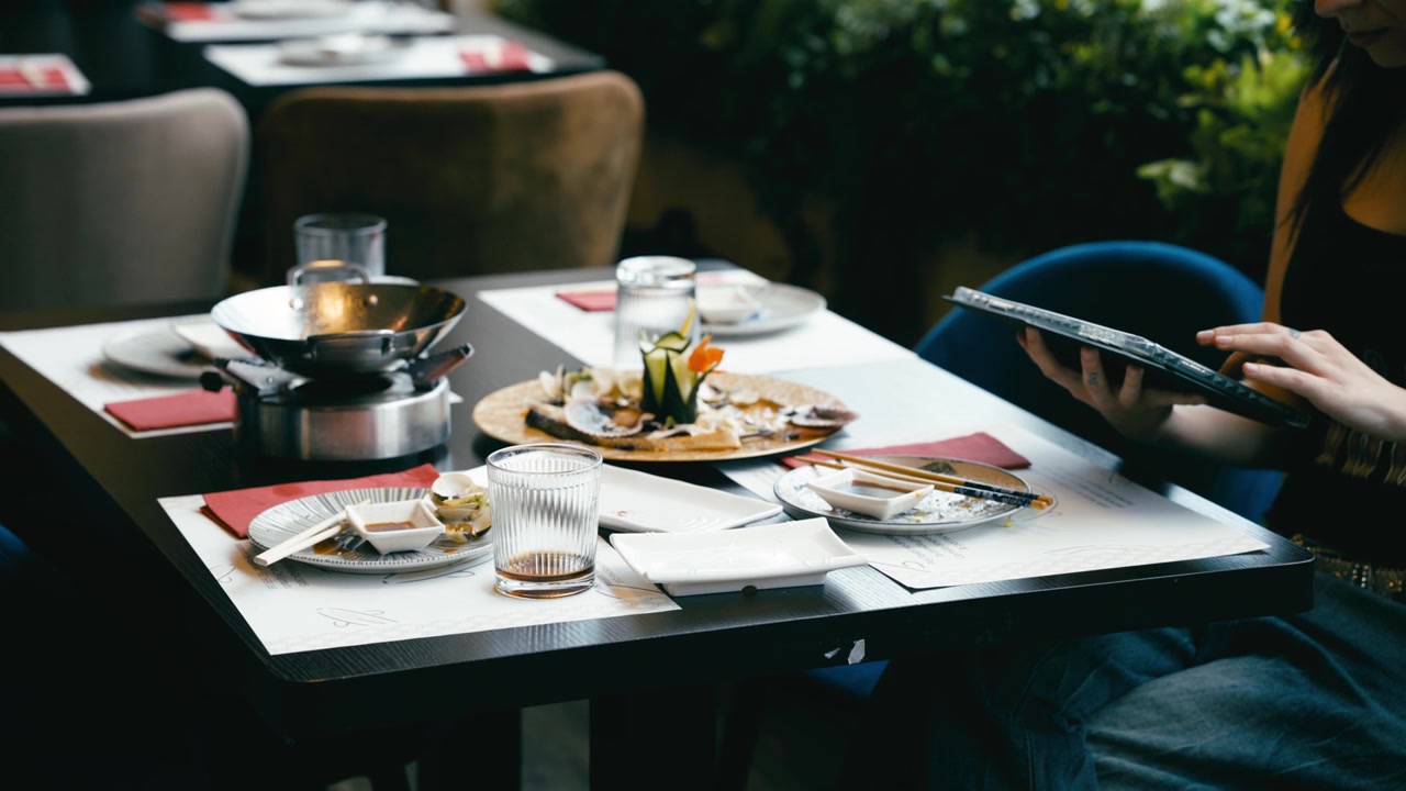 Kvinde bruger tablet ved restaurantbord med mad