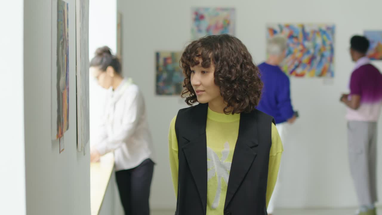 Young Woman Observing Artworks in Gallery