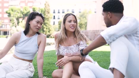 multiethnic friends talking while sitting at city park during daytime