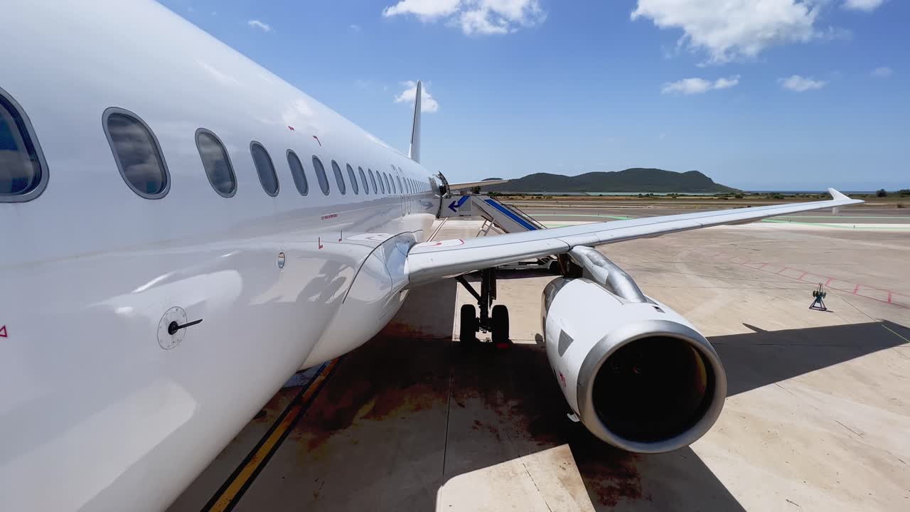 vista inclinada hacia arriba desde la puerta delantera del ala del fuselaje y el motor del avión estacionado en el aeropuerto de las islas baleares de ibiza con escaleras adjuntas en un día soleado