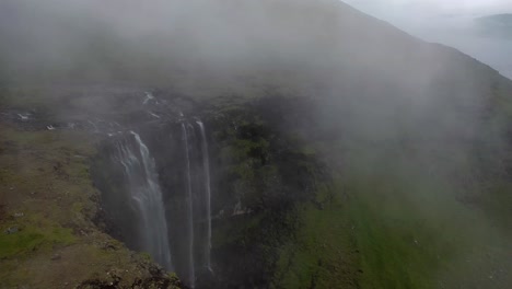 Aerial-flight-over-top-of-misty-Fossá-Waterfall-on-Faroe-Islands-coastline