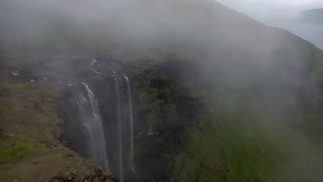 aerial flight over top of misty fossá waterfall on faroe islands coastline
