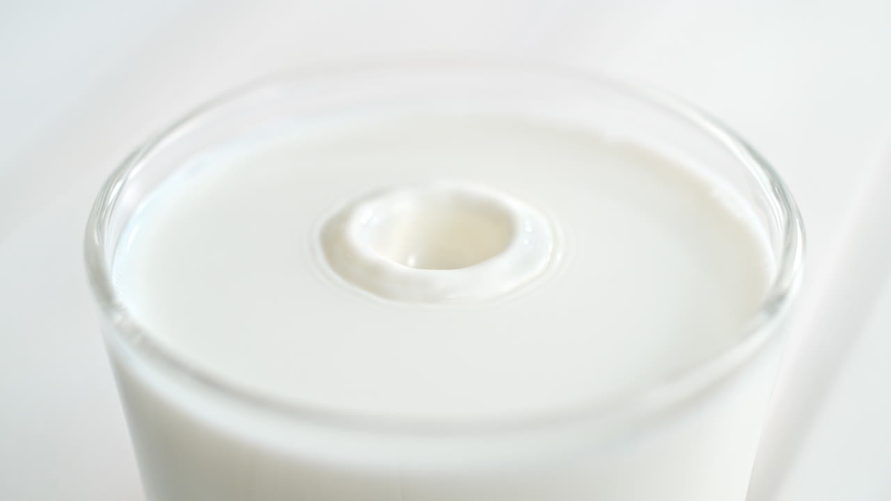 밝은 부 테이블에 우유 한 잔과 물방울이 느린 속도로 스플래시를 만들고